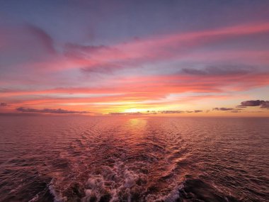 A scenic pink sunset above the blue sea with calm waves