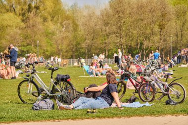 The women resting on green grass next to their bicycles in the park in Poznan, Poland