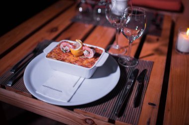 Masadaki parlak tencerede deniz ürünleri lazanyası.