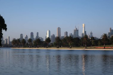 A scenic view of a calm coast and city skyline under a clear sky
