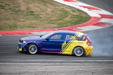 BMW E87 1 Series drifting on the circuit, it is blue and yellow color