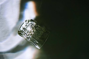 A closeup shot of glass lying on its side with shadow in dark background