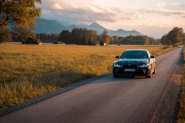 Günbatımında modern bir BMW M4 'ün, Dağ v. lüks spor arabalı görüntüsü birçok sürücünün hayalindeki arabadır.