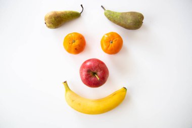 A closeup of various fruits isolated on white background. A smiley face.