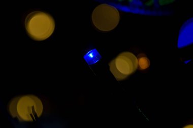 A soft focus of a blue Christmas string light bulb with dark bokeh background