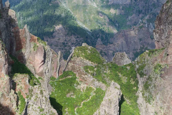 Hikers in colorful clothes walk through the rugged mountain landscape of Madeira on their way to Pico Ruivo