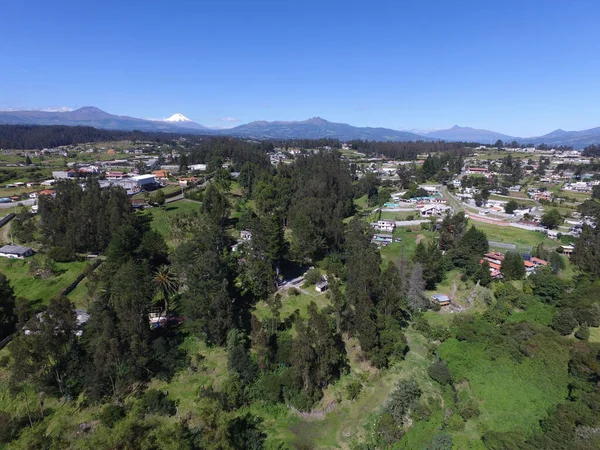 Güneşli bir günde yeşil ormanlarla kaplı tepelerin ve kırsal alandaki evlerin kuş bakışı görüntüsü