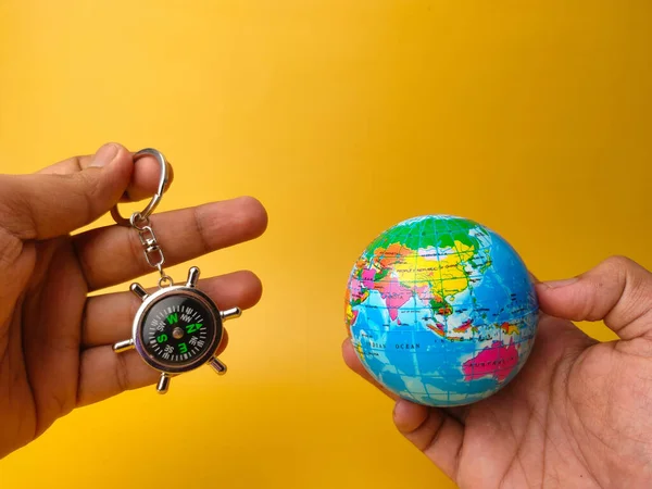 Adult Hands Holding Compass Keychain World Globe Yellow Background Holidays — Stockfoto