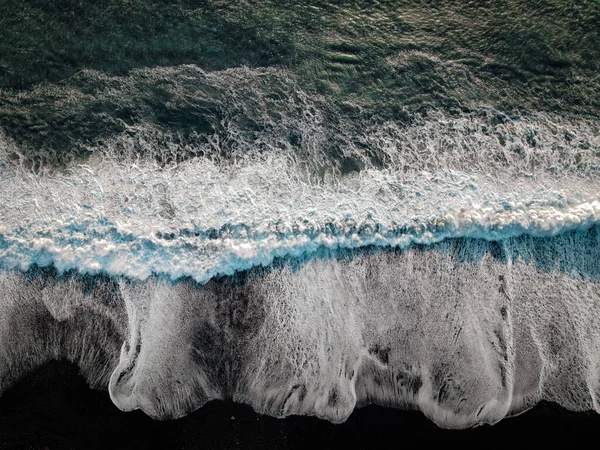 An aerial top view of waves and foam in a sea