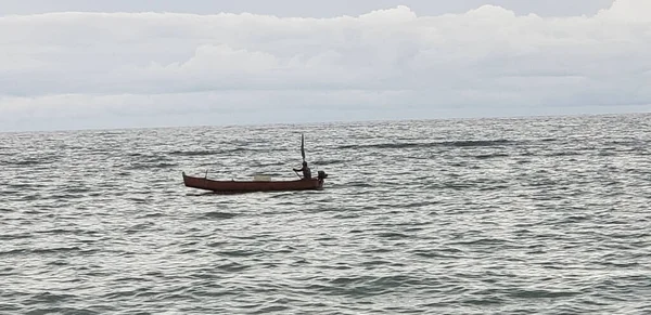 A small fishing boat in the middle of the sea against the horizon