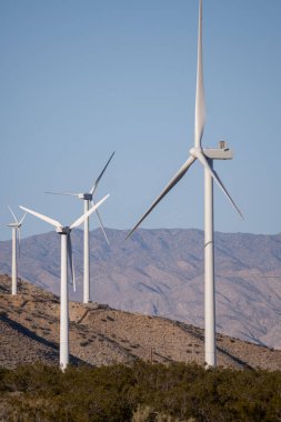 Palm Springs, Kaliforniya 'da mavi gökyüzü arka planındaki bir çiftlikte dikey yel değirmeni çekimi.