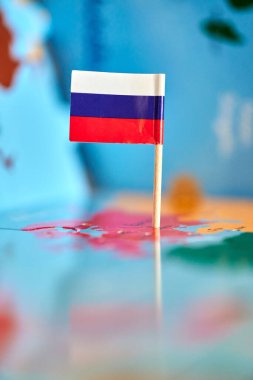 A closeup of a flag of Russia with a small stick on the map