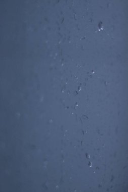 A vertical shot of a blue wall with drops of water on it