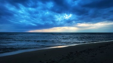 A beautiful sunset view from sandy beach under a blue cloudy sky