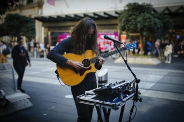 Gitar çalan ve sokaklarda şarkı söyleyen bir sokak müzisyeni.