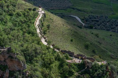 sunny scenery of a tourist road in the mountains with people taking pictures in the background