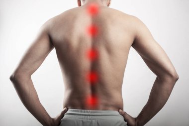 Healthy young man suffering from spinal cord injury, backache , pain on spine highlighted in red spot. cropped human body part pain.