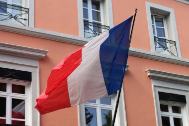 The French flag flying in front of a coral pink house