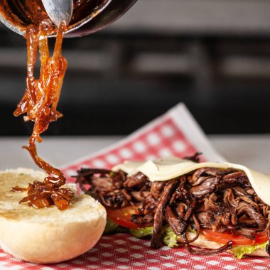 A close-up shot of the process of making a burger with meat and vegetables