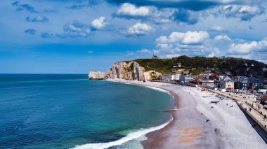 Kumlu bir sahilin yanında binaları olan güzel bir okyanus manzarası.