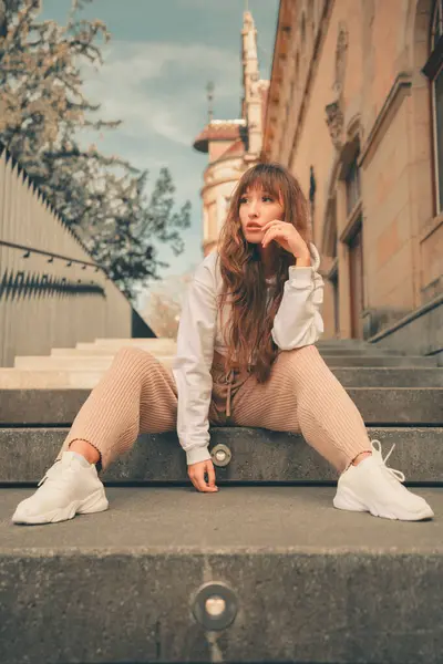 A vertical shot of a white Caucasian girl with stylish clothing posing for a picture
