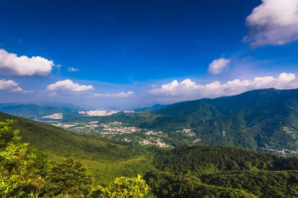Dağ sıralarının güzel manzarası ve altında bulutlu gökyüzü olan bir kasaba.