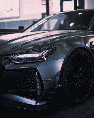 A vertical shot of a gray luxury car parked in the garage
