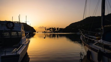 A bright yellow sunset sky over a calm pier