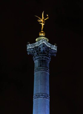 A low angle shot of the Place de la Bastille Tower in Paris, France at night