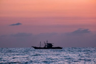 A boat sailing in the sea with the stunning sunset sky in the background