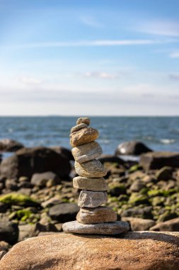 A vertical closeup of the rocks stacked on top of each other against the sea. Selected focus.