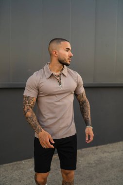 Bej tişörtlü ve siyah şortlu genç bir adamın dikey çekimi.