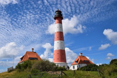 A beautiful view of a lighthouse surrounded by a field under a blue sky