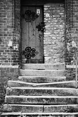 A vertical black and white shot of the entrance of an abandoned psychiatric department building
