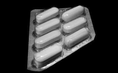 Macro shot of generic white pills medications on black background. Pharmaceutical industry.