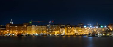 A panoramic view of a row of illuminated buildings in the city at night