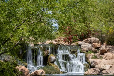 A beautiful scene of a cascade waterfall in the park with rocks and green trees in the background