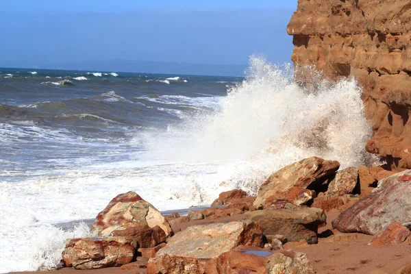 岩の多い海岸や崖に泡立つ波 — ストック写真