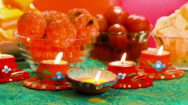 Colorful Diwali oil lamps, Deepavali oil lamps lighted in beautiful formation with bowls full of different Diwali sweets . Decorative Colorful Diya