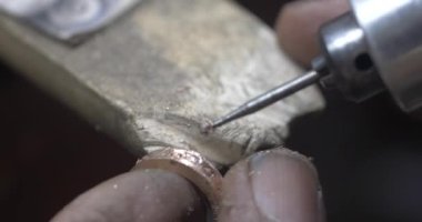 Jakarta, Indonesia-June 19, 2022: The process of making gold rings by traditional craftsmen by making holes in the ring for the ring eye