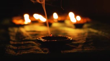 Diwali Diya oil lamps are placed on a table among other glowing Diya lamps. Decorative Diya lamps.