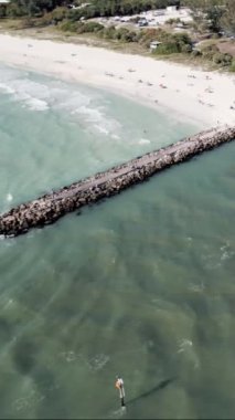 A vertical aerial view of pathways in the ocean with a town in the background
