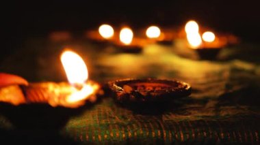 Diwali Diya oil lamps are placed on a table among other glowing Diya lamps. Decorative Diya lamps.