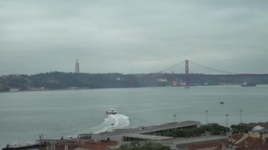 A beautiful shot of a ship sailing in the sea with a bridge on the other side under cloudy sky