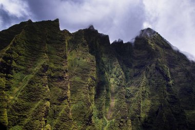 A low angle shot of a green rocky mountains against cloudy sky in a sunny day in Kaua'i Island, Hawaii, United States