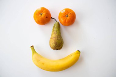 A closeup of various fruits isolated on white background. A smiley face.