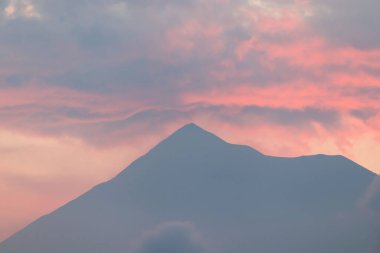 Beautiful sunset clouds above silent volcano de fuego seen from a distance in antigua guatemala.