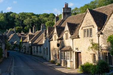 The brown stone cottages surrounded by green vegetation. Castle Combe, England, UK.