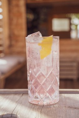 A vertical closeup of a glass of fresh iced summer cocktail on the wooden surface