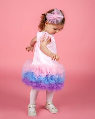 A cute stylish Caucasian girl posing on a pink background